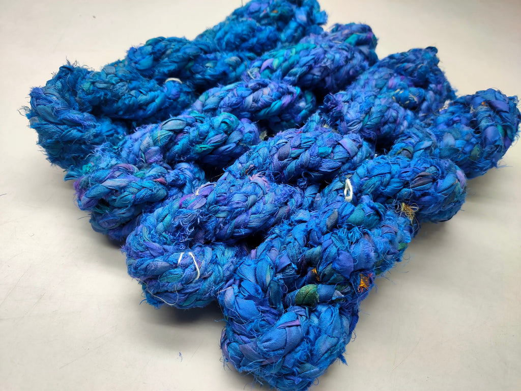 Braided Sari Silk Ribbon yarn is made of pure silk and is approximately an inch wide through out. Due to its handmade nature there might occasionally be variations in width. When silk fabric is cut and made into saris, wraps, and veils, there is always a bit left over. Rather than throw that waste fiber into the trash, it has been made into a beautiful, unique, soft yarn..!! Direct from India, this yarn is a truly recycled product. It is a bulky weight and is soft and easy to knit or croc